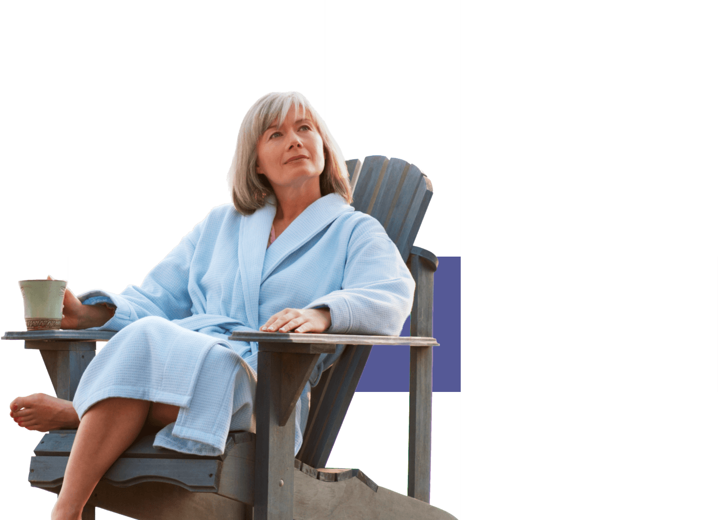 Image d’une femme en robe de chambre assise dans une chaise Adirondack qui regarde paisiblement au loin